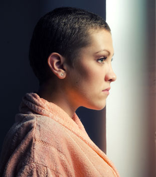 female young person wearing orange and looking out of the window. image of support for cancer patients female young person wearing orange and looking out of the window. image of support for cancer patients
