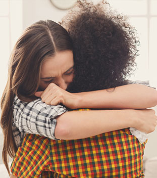 sisters in flannel shirts hugging and are upset. image for cancer support for families sisters in flannel shirts hugging and are upset. image for cancer support for families