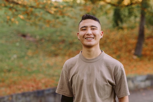 young person smiling and standing in the park