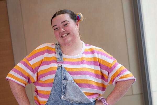 Abbey, a young Australian who has benefited from Canteen's free cancer help, smiling at the camera wearing dungarees